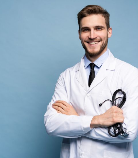 Portrait of confident young medical doctor on blue background